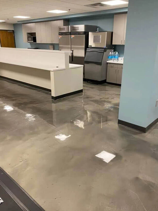 Polished grey epoxy floor in a commercial kitchen and breakroom with stainless steel appliances